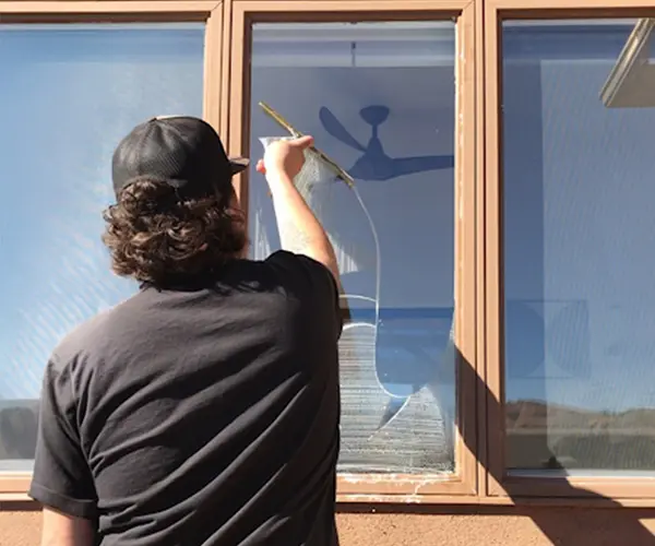 view of back of a man wiping a window clean