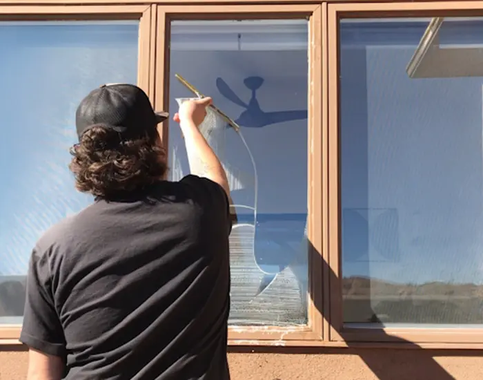 view of back of a man wiping a window clean